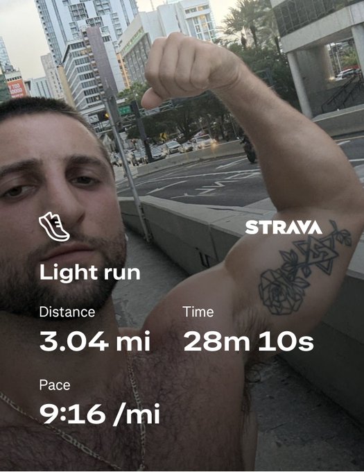 A shirtless man flexes his arm, revealing a lotus tattoo, in a Strava screenshot showing a "Light run" of 3.04 miles in 28m 10s at a 9:16/mi pace on a city street—capturing the casual, self-aware fitness brag vibe of the "on my JSIMULA3 shit" caption.