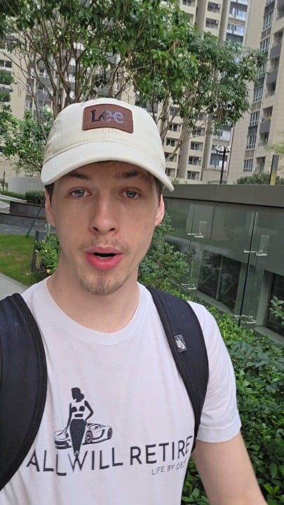 The image features a man wearing a white baseball cap with a logo, standing outdoors near some buildings. He has a backpack on his back and appears to be posing for a photo. The caption "All Will Retire" is written below the image, which suggests that the man might have an interest in or connection to the message of the post.