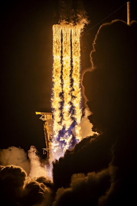 Nighttime photograph of a rocket launch with bright orange flames billowing into clouds of smoke.