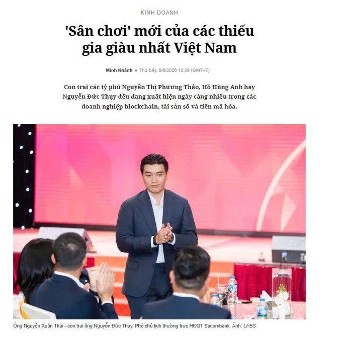 The image features a man standing at a podium with his hands clasped together, giving a speech or presentation. The text "Kính Doanh" can be seen in the image as well. In the background of the photo, there are people sitting around a dining table, possibly attending an event or gathering related to the speaker's topic.