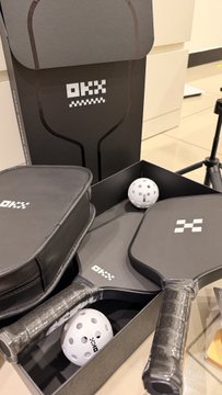 A collection of OXX brand pickleball paddles, balls, and accessories displayed on a store shelf.