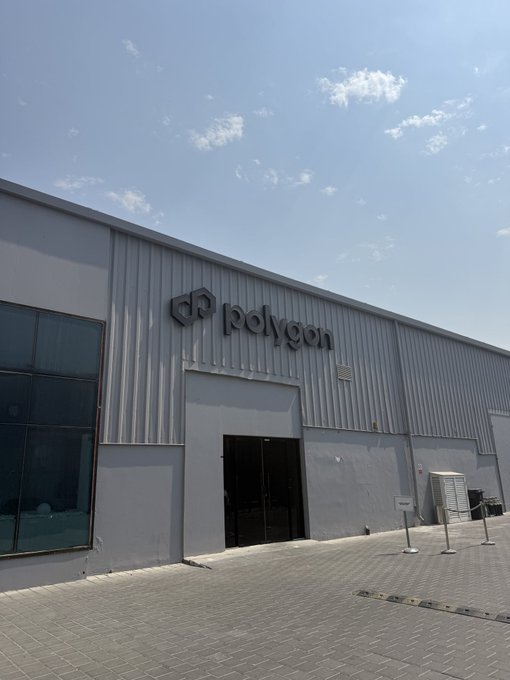 The exterior of Polygon's Dubai office, prominently displaying the "polygon" logo on a modern gray industrial building under a bright blue sky.

The image shows the entrance to Polygon's Dubai-based offices, visually reinforcing the post's celebration of the company's regional presence and its role in bridging crypto with traditional finance—elements of the "Open Money Stack" the author highlights.
