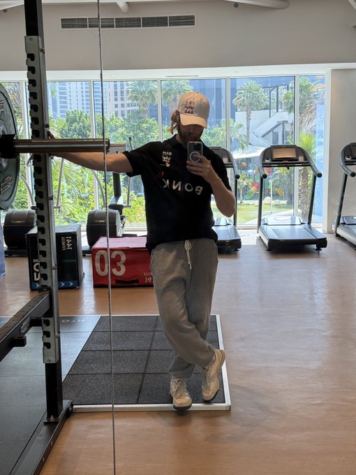 The image features a man taking a selfie with his phone while standing in front of a weight machine at a gym. The man is wearing a black shirt, gray sweatpants, and white sneakers. In the background, there are several exercise machines such as treadmills and dumbbells, indicating that this is an active fitness center. The post caption reads "those @monad mfs got that dog in them", which seems to be a reference to a popular social media account or a person named Monad MFS who has gained attention for their fitness journey.

The man's selfie captures his interest and possibly his admiration for the gym environment, as he poses with his phone while surrounded by various exercise equipment. The image also highlights the importance of staying active and maintaining a healthy lifestyle through regular physical activity at a gym setting.