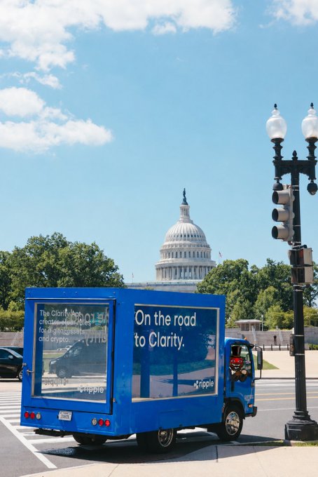 A blue Ripple-branded truck with the slogan "On the road to Clarity" and Ripple's logo parked on a street in Washington, D.C., with the U.S. Capitol Building visible in the background, promoting the company's advocacy for the Clarity Act to Congress.