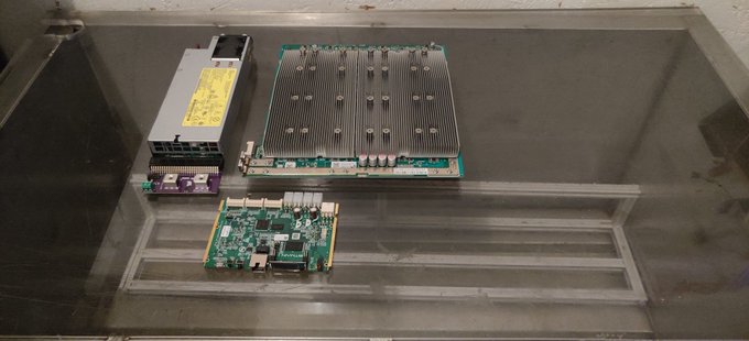 Server hardware components including a power supply unit, a large processor/motherboard assembly with prominent heatsinks, and a smaller circuit board displayed in what appears to be a server rack or equipment case, fitting the "BTC Tech Nerd Army" theme by showcasing the mining/tech hardware infrastructure behind cryptocurrency operations.