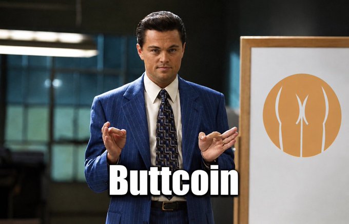 The image features a man dressed in a suit, standing in front of a whiteboard with the word "Buttc­ coin" written above him. The man appears to be giving a presentation or speech related to cryptocurrency.