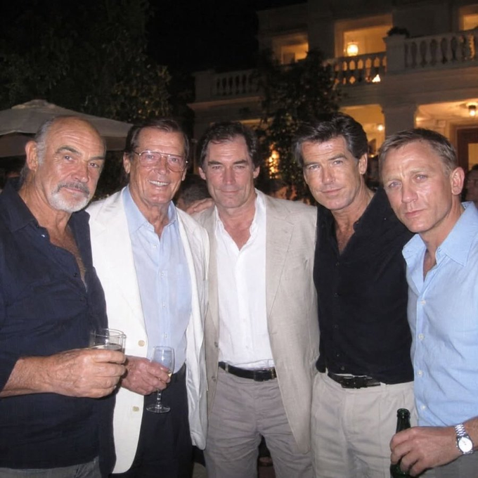 A vintage photograph of five distinguished older men, including Sean Connery and Roger Moore, posing together at an evening event, dressed in suits and smart casual attire, with some holding drinks.