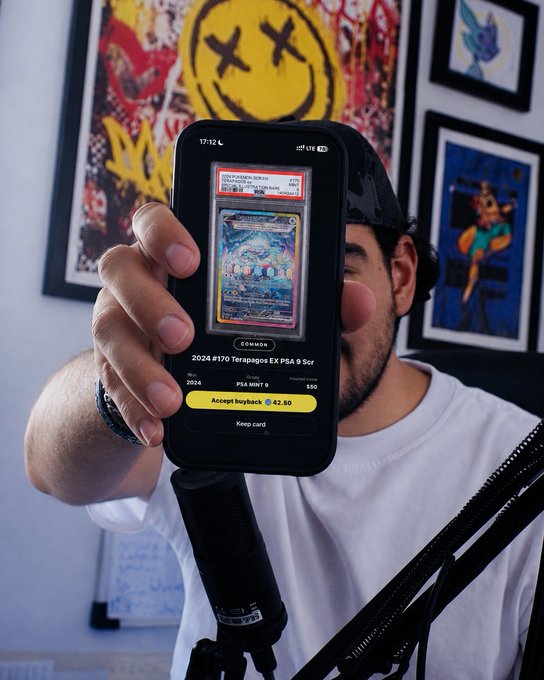 A person holds up a smartphone displaying a graded Pokémon trading card on what appears to be a marketplace app, showing a 2024 #170 Terrapagos EX PSA 9 card priced at $50 (buyback $42.50). The image ties to the post's Solflare pack-ripping theme, with the person in a room decorated by pop art, including a prominent X-eyed smiley face print.
