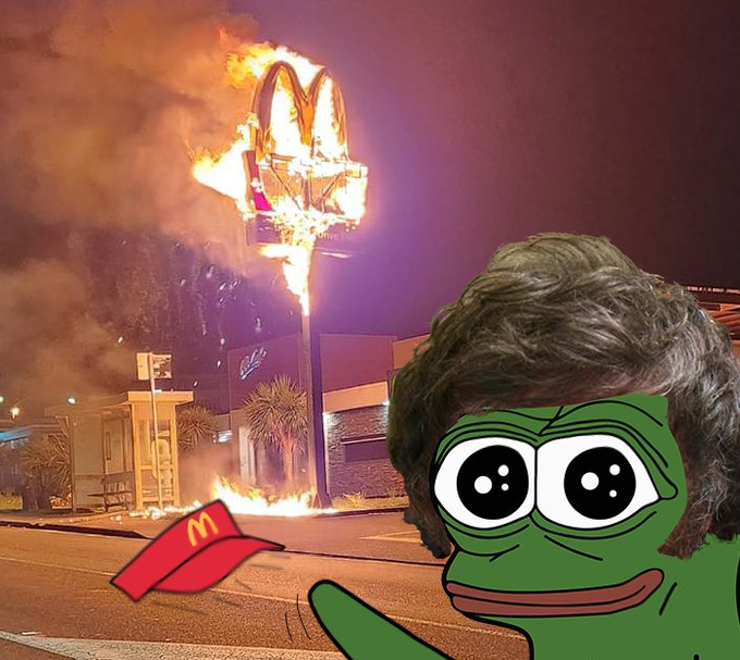 A meme image featuring a Pepe the Frog character with sad eyes and a small red McDonald's hat, set against the backdrop of a burning McDonald's sign at night.
