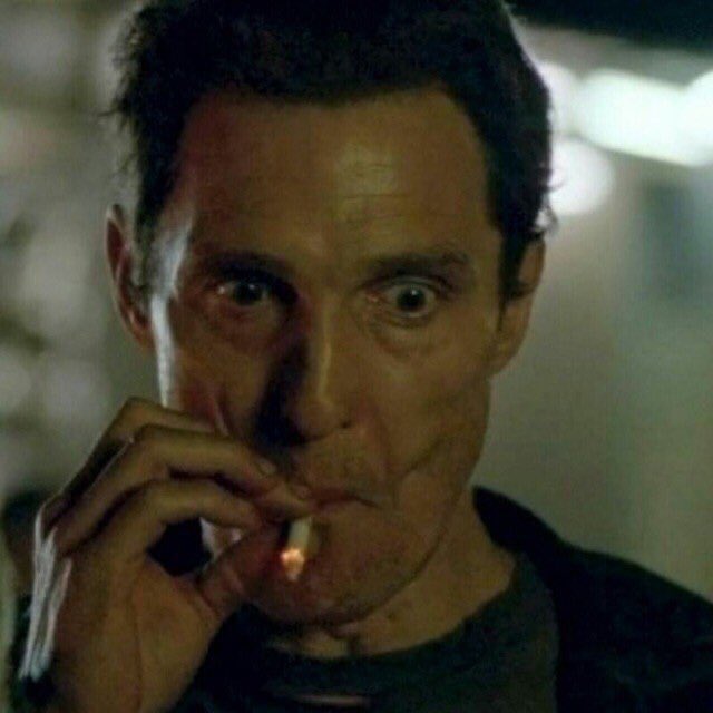 A close-up of a screaming man smoking a cigarette in a dimly lit setting.