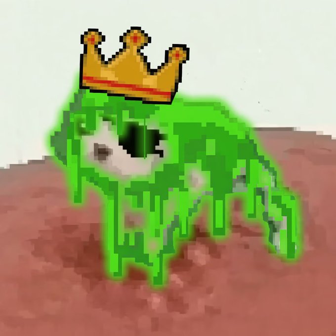 Pixelated green frog-like creature wearing a gold crown sitting on a brown surface.