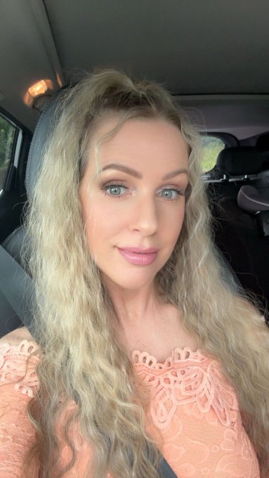 A blonde woman takes a selfie inside a car, wearing a peach-colored lace top with an off-the-shoulder neckline, reflecting the post's weary but resilient tone as she signs off for the weekend despite a challenging week of low engagement and market downturns.