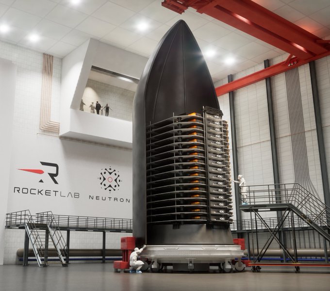 A massive black Neutron rocket payload fairing stands in a RocketLab assembly facility with "ROCKETLAB" and "NEUTRON" logos displayed on the wall, as technicians inspect a stack of Flatellite satellites fitted inside—directly illustrating RocketLab's newly awarded $397M U.S. Space Force contract to build and launch the Flatellite constellation for real-time airborne threat tracking.