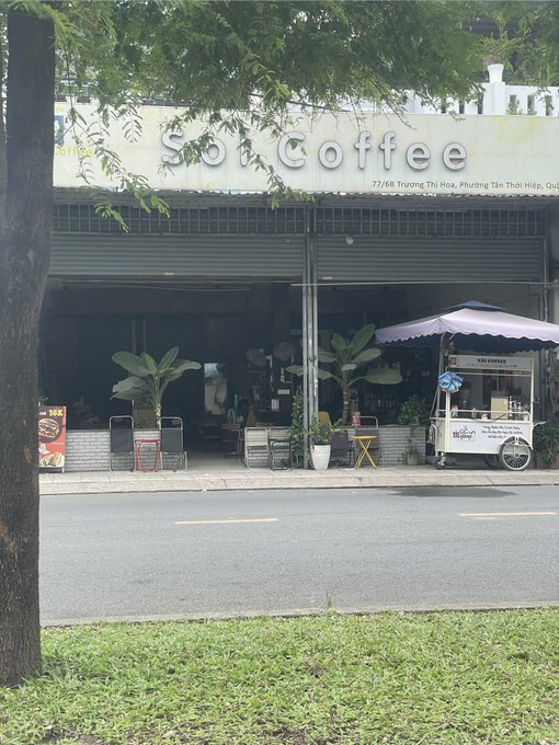 An outdoor view of a So Coffee café storefront with an adjacent Vinamilk vending cart on the sidewalk.