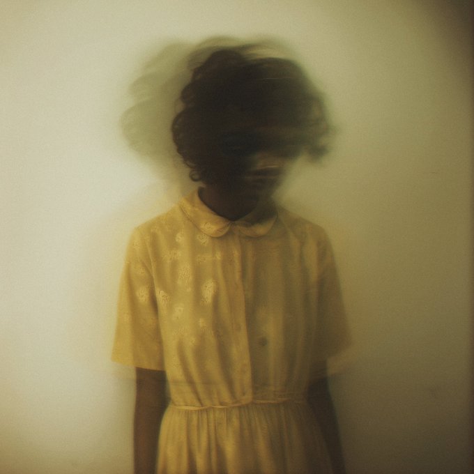 The image features a person wearing a yellow dress standing against a white wall. The person's face is partially obscured by their hair, giving them an ethereal appearance. The background of the photo appears to be blurry or indistinct, further emphasizing the focus on the individual in the foreground. The image seems to be related to the "Good morning Ghostly Haze" series, as indicated by the post title and the use of the word "Available".