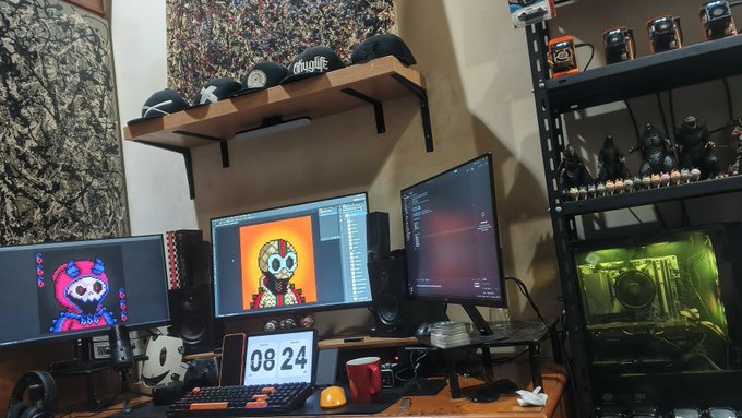 A multi-monitor computer setup on a desk featuring digital art of skull characters on two screens, with a green-lit PC tower, shelves of caps, and speakers visible in the background.