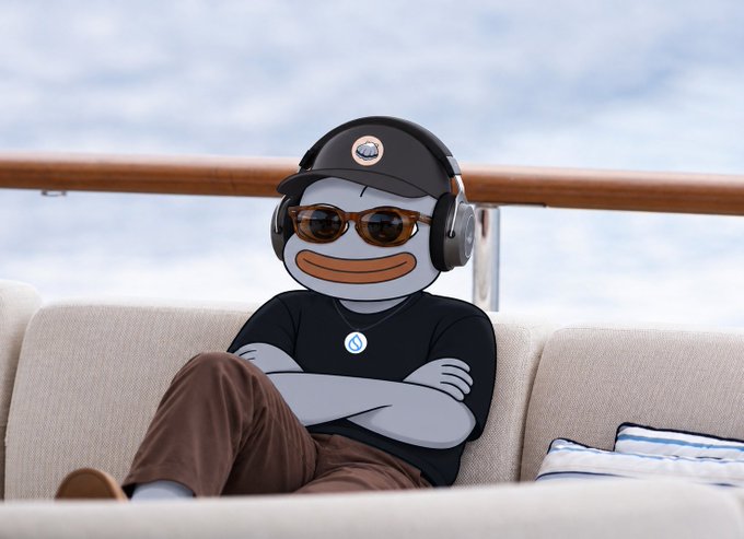 An illustrated cartoon character with a gray, stylized face and orange lips sits relaxed on a couch, wearing sunglasses, a black cap, headphones, and a black t-shirt featuring a logo.
