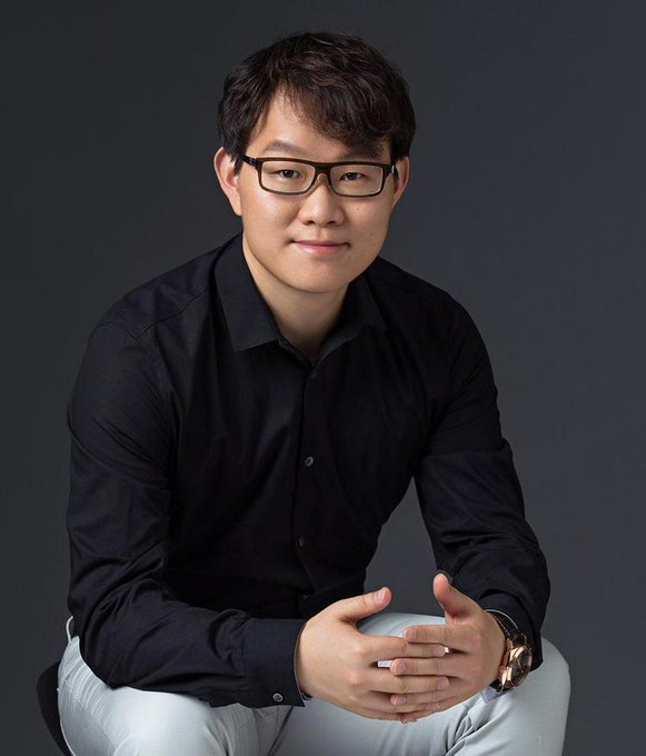 Huobi founder Leon Li sits in a black shirt and glasses during a professional portrait, posing against a dark gray background. The image accompanies news of his massive £51 million profit from selling his London mansion in Regent's Park.
