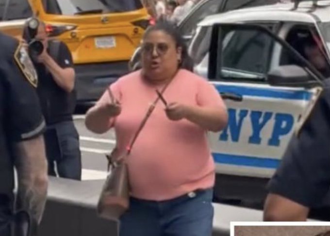 A woman in a pink t-shirt and sunglasses gestures animatedly while standing in front of an NYPD patrol car, with a police officer in the background. The "POV: You're a degen ready to cook" caption humorously frames her intense, almost combative expression as that of a high-stakes trader gearing up for market action.