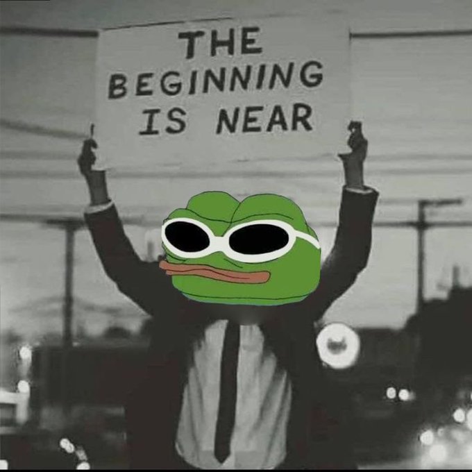 A black and white image of a man in a suit holding a sign reading 'THE BEGINNING IS NEAR', with his face replaced by a Pepe the Frog meme wearing sunglasses.