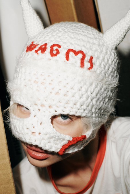 A person wearing a white knitted balaclava with devil horns and red stitched designs, featuring text that resembles 'A$AP Mob'.