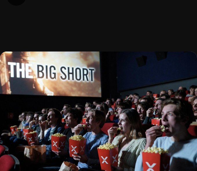 A cinema audience eats popcorn while watching a screening of "THE BIG SHORT." The image cleverly ties into the post's theme of "shorting," referencing both the film's title about the financial crisis and the hashtags #XRP and #RCT related to short-selling or bearish trading sentiment.