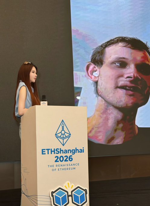 A woman with long hair stands at a podium labeled "ETHShanghai 2026 - The Renaissance of Ethereum" beside a large projected image of a man's face, illustrating the post about her role as the event's lead organizer handling venue payments and coordinating speakers for the Ethereum Shanghai conference.
