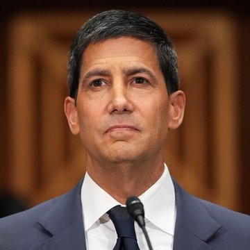 A man in a dark suit and tie speaks at a podium with a microphone, appearing to deliver a formal address or testimony. The image likely depicts a Federal Reserve official, fitting the post's context about upcoming Treasury bill purchase operations totaling $14.612 billion.