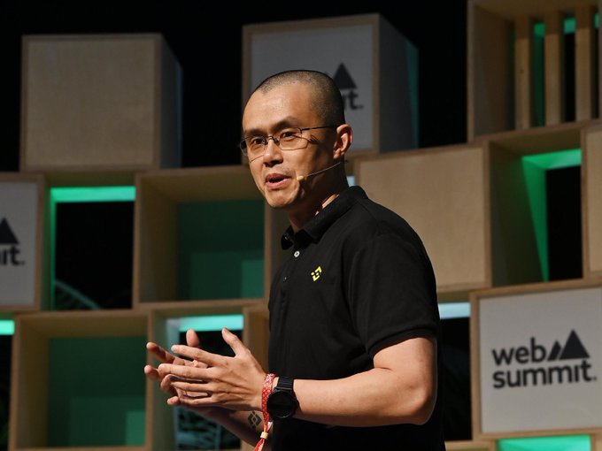 A man with glasses and a black polo shirt speaks on stage at a Web Summit event, with the "web summit" logo visible on the wooden cube backdrop. He gestures with his hands as he discusses the future of finance, particularly the role of stablecoins and tokenized gold as foundational elements of the next financial era.