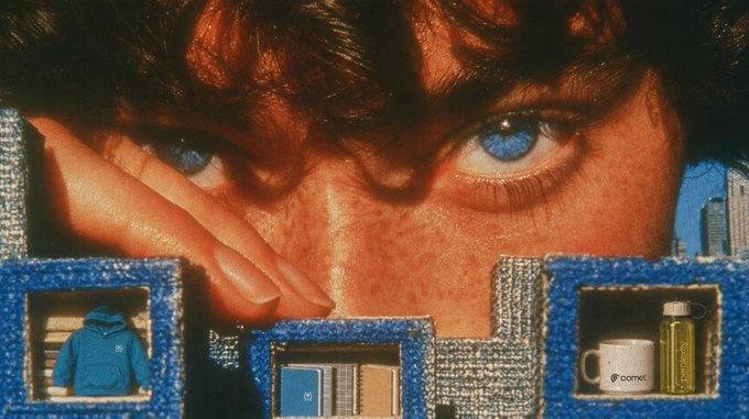 A vintage-style image showing a close-up of a person's blue eyes looking through a blue, castle-like structure displaying merchandise including a blue hoodie, notebooks, and a 'comet' branded mug and water bottle.