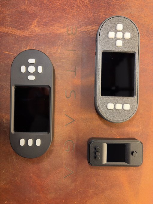 Three black SeedSigner hardware wallets in Plus and Premium variants are displayed on a brown leather surface, with visible "EST. VG" embossed in the background. The image showcases the larger Plus models with their button arrays and screens, alongside a smaller smartcard version, illustrating the product lineup described in the post from Bitsaga.