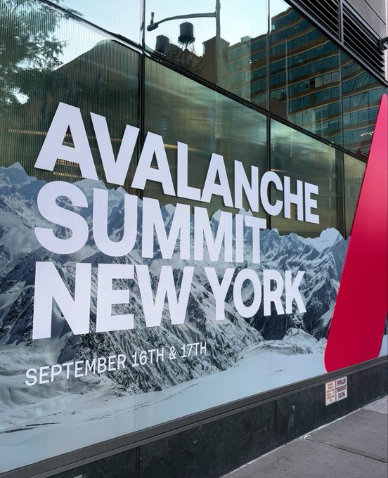 An outdoor advertisement on a glass building for 'AVALANCHE SUMMIT NEW YORK' taking place on 'SEPTEMBER 16TH & 17TH', featuring a snowy mountain graphic and a red Avalanche logo.