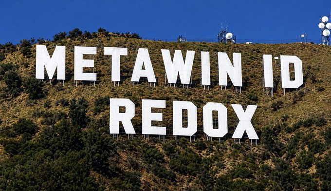 The iconic white "METAWIN ID REDOX" letters are displayed prominently on a hillside, with the post announcing a $250 prize sent to user @amredox's MetaWin balance, using "REDOX" as a creative caption for the MetaWin casino giveaway.