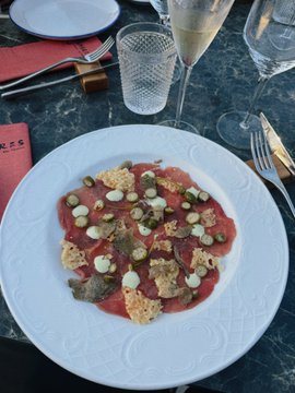A plate of carpaccio is pictured, likely celebrating the confirmation that the $HYPE bottom is in on Hyperliquid after a quant team discussion. The image represents a celebratory meal following positive market news.