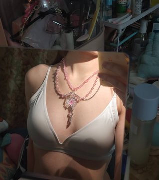 The image shows a person taking a mirror selfie wearing a white bikini top, showcasing a pink beaded chain necklace with a heart-shaped pendant. The necklace is the clear focus of the photo, complementing the caption's excitement about discovering how to style and appreciate the piece.