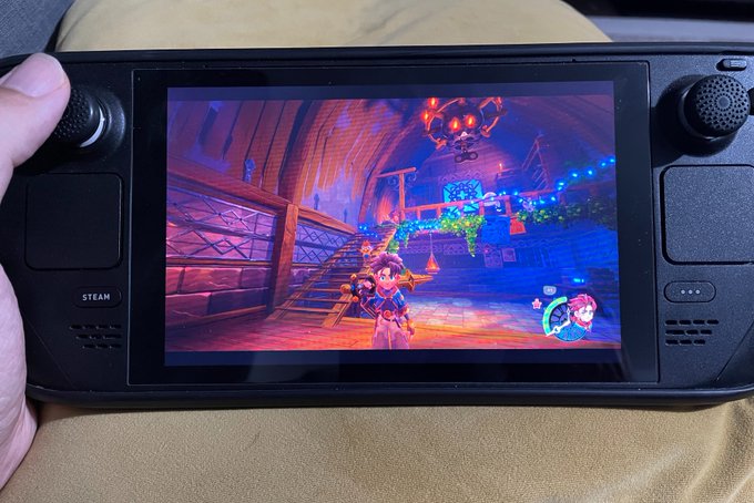A Steam Deck handheld gaming device displaying what appears to be a colorful platformer video game on its screen.