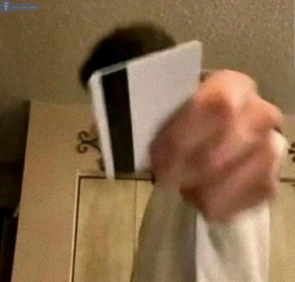 A blurry fist clutches a credit card in a frantic, oversized motion toward the camera, humorously depicting the panicked reaction of degen traders rushing to buy the dip. The exaggerated hand and shaky framing amplify the chaotic, impulsive energy behind the joke.