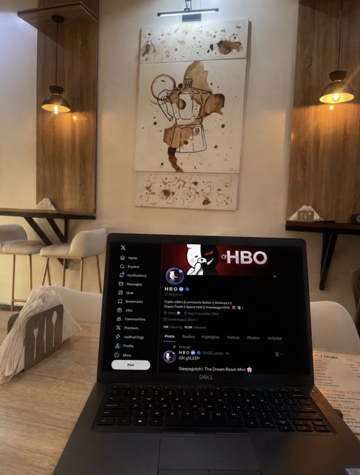 The image shows a laptop computer sitting on top of a table, with a painting hanging above it. The laptop screen displays a Twitter account that says "GN gTRIA $Tria: AI Agent Settlement Layer @usetria scales its autonomous execution framework to support high-velocity asset spending and routing for AI software clients". This image is related to the post because it features an AI agent settlement layer, which is a component of the Twitter platform. The painting above the laptop adds artistic elements to the scene while also serving as a visual representation of the AI agent settlement layer in the context of the Twitter account's content.