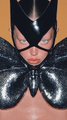 An illustration of a female character wearing a black mask and a textured black outfit with a plunging neckline.