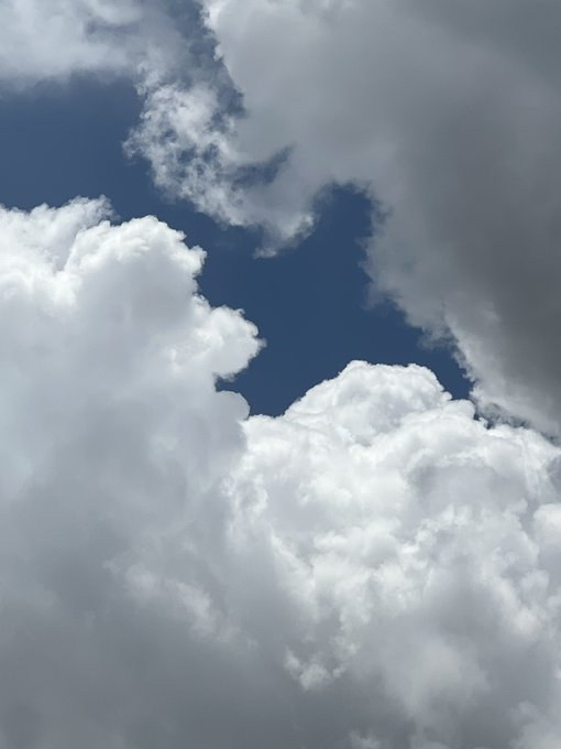 Towering white cumulus clouds frame a patch of deep blue sky, creating an expansive and dynamic atmosphere. The image's open, airy quality visually echoes the post's message about liquidity and stablecoin infrastructure—both representing vast potential space where adoption and integration must take shape to become meaningful.