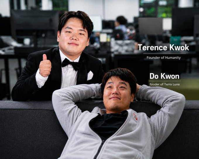 The image features two men posing for a photo with one man wearing a tuxedo and bow tie while the other wears a gray sweatshirt, both smiling at the camera. The caption of the image reads "I don' know why, but the Humanity founder is giving me Do Kwon vibes :))".
