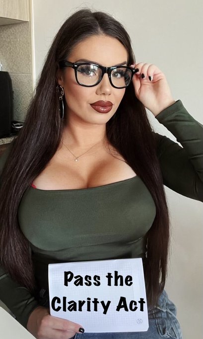 A woman with long dark hair, wearing glasses and an olive green top, holds a handwritten sign reading "Pass the Clarity Act" while touching her glasses, visually supporting the post's call to action for the legislation to be passed.