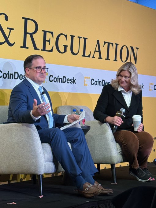 A man in a navy suit and a woman sit on stage during a CoinDesk "Policy & Regulation" panel discussion, with the backdrop prominently displaying the event title and CoinDesk branding. The scene aligns with the post, which describes a fireside interview with Senator Lummis highlighting her leadership in advancing digital asset policy.