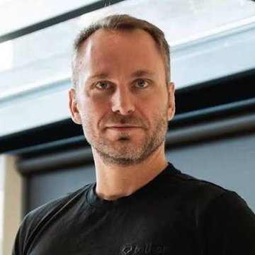 A man with short brown hair and a beard, wearing a black t-shirt with "mill of" partially visible, stands indoors in what appears to be a professional setting. The image likely depicts Paolo Ardoino, the Tether CEO mentioned in the post about USDT expanding to the Bitcoin network.