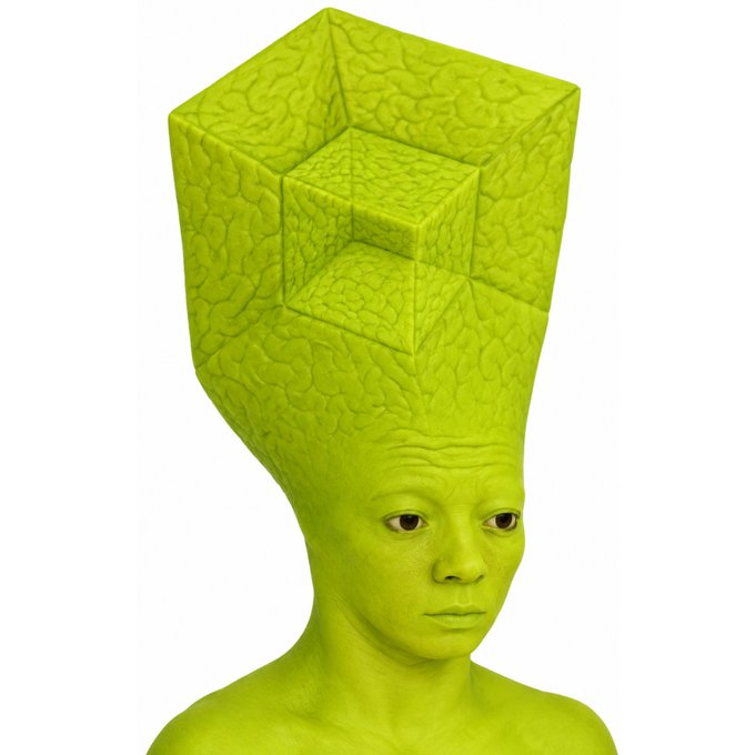 A surreal 3D render of a green-skinned figure whose head extends upward into a tall, textured cube-like structure.
