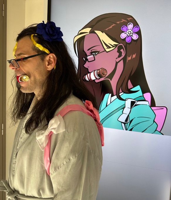 A side-by-side comparison showing a man with long dark hair, a flower headband, glasses, and a pacifier next to an anime-style illustration of a woman with glasses and a gag.