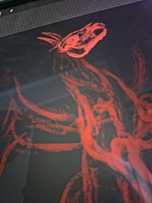 A red brushstroke drawing of a figure on a dark background, with a cutting mat visible at the top edge.