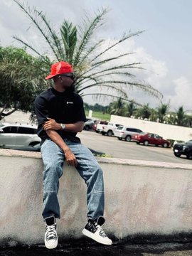 A man in a red hard hat and sunglasses sits casually on a wall, with palm trees and a parking lot of vehicles behind him. The image relates to the post's theme of "defining growth," symbolizing progression, ambition, and forward momentum through the construction hat and relaxed yet purposeful pose.
