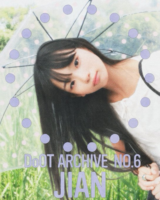 A photo book cover titled "DoOT ARCHIVE NO.6 JIAN" featuring a young woman with long dark hair holding a transparent umbrella decorated with purple polka dots against a grassy background.