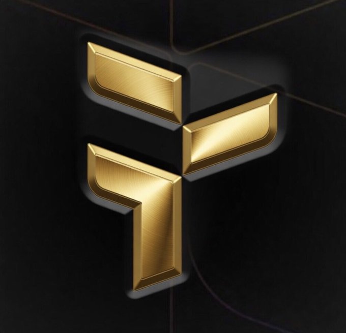 The image features a striking gold logo with three vertical lines, each adorned with a small circle at the top. The letters "F" are prominently displayed within these circles, creating an elegant and eye-catching design. The background of the image is black, which contrasts beautifully with the golden elements of the logo. In the bottom right corner of the image, there's a text that reads: "Tria took all the major chains and memes and created a cross chain liquidity pool, assets flow and you don't ever see the bridges". This phrase highlights the uniqueness and innovation behind the creation of this gold-themed logo.